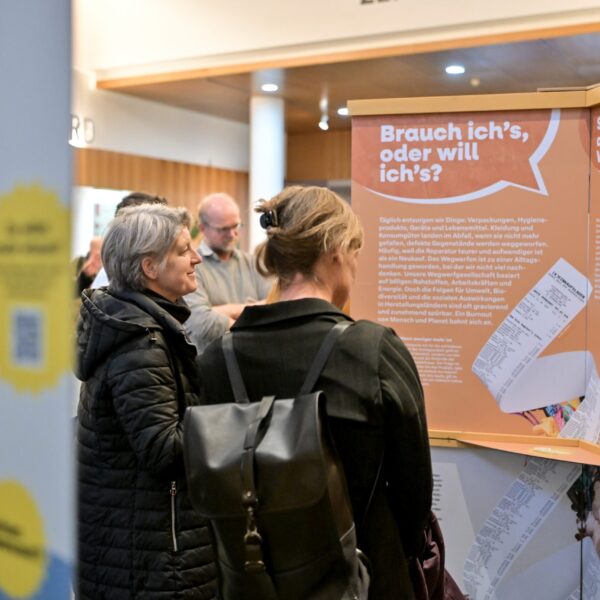 Besucherinnen stehen vor einer Ausstellungstafel und lesen den Inhalt