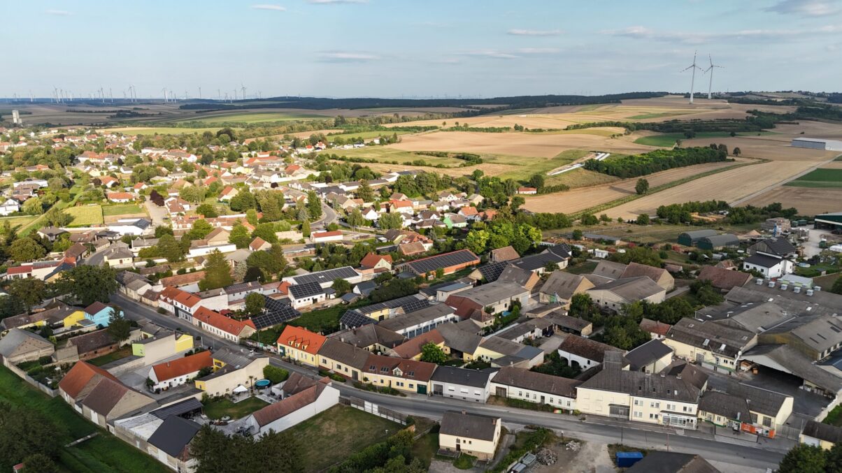 Gemeinde im Weinviertel mit Photovoltaik auf Dächern und Windräder im Hintergrund