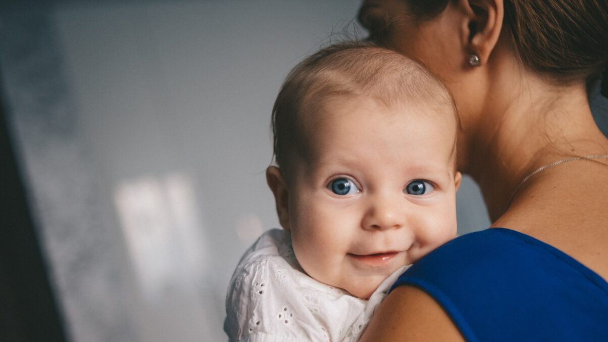 Lächelndes Baby am Arm seiner Mutter