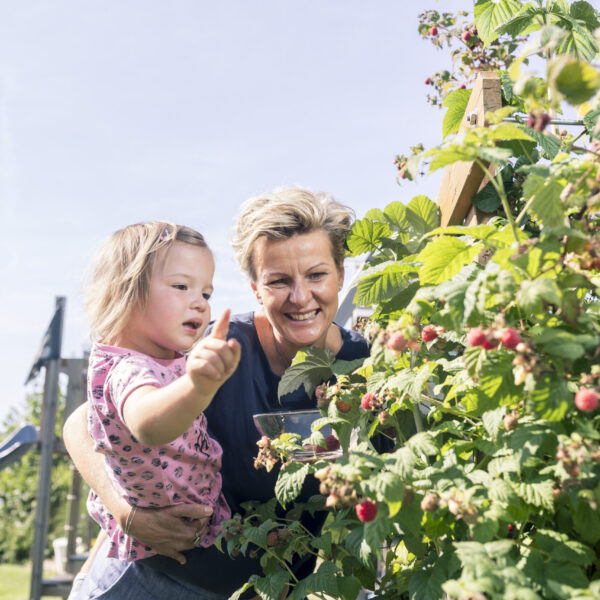 Mutter mit Kind bei Himbeerstrauch