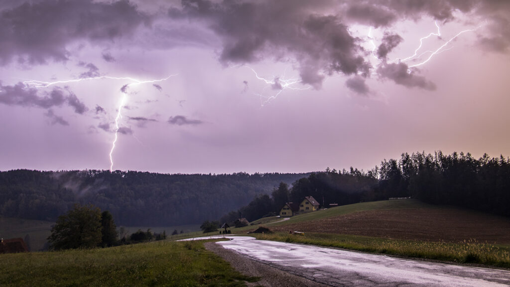 Hügelige Landschaft bei einem Unwetter mit Regen und Blitzeinschlägen